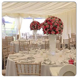 This is a picture of pink and white Wedding table flower displays in situ at a wedding reception.