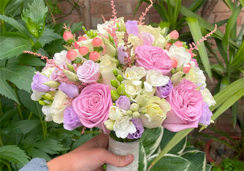 This is a picture of a Wedding Flower Tied Bouquet in pastel shades using Roses, Freesia, Lisianthus and Hypericum.