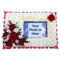 Photo Frame Funeral Flower Tributes which have a space for a photograph or picture of a loved one. The edge is covered with flowers and greenery.