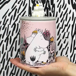Moomin Limited Edition Pink Love Jar. A beautiful jar featuring an adorable 3D sculpture of Moomin and Snorkmaiden sitting on top of a contrasting grey lid. The body of the jar comes in a soft pink, featuring a classic  Moomin and Snorkmaiden print and is