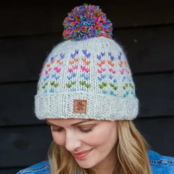 Pachamama Knitwear Andorra Oatmeal Bobble Beanie rollback handknitted hat, made from 100% wool with a partial fleece lining, featuring miniature multicoloured hearts.