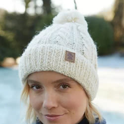 Pachamama Knitwear Chamonix Bobble Beanie Cream, handknitted, made from 100% wool with a fleece lining using traditional cable knit techniques.
