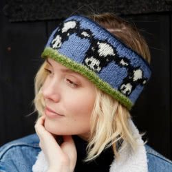 Pachamama Knitwear Dairy Cow Headband ear warmers featuring Friesian cows on a blue and green background, 100% wool, fleece lined.