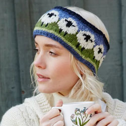 Pachamama Knitwear Flock of Sheep Headband ear warmers, featuring white sheep on a green and blue background, 100% wool, fleece lined.