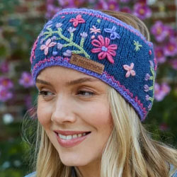 Pachamama Knitwear Sunflower Headband ear warmers featuring a navy blue background with embroidered colourful flowers, hand knitted, 100% wool, fleece lined.