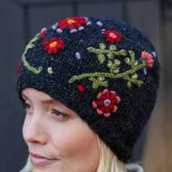 Pachamama Knitwear Lugano Beanie Charcoal hat featuring hand embroidered flowers on a black background, 100% wool, fleece lined.