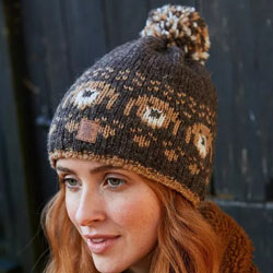 Pachamama Knitwear Pooch Dog Bobble Beanie Bark Hat features a bark-brown background with a row of knitted pooch heads, 100% Wool, fleece lined