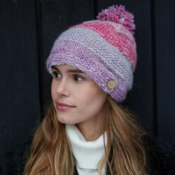 Pachamama Knitwear Sierra Nevada Bobble Beanie Pink, Handknitted from wool and mohair, lined with Sherpa fleece for extra warmth and comfort. Coming in bands of pink, lilac and cream finished with a pink and lilac fluffy bobble.