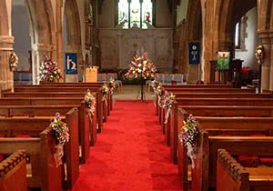 This is a picture of Wedding Flower pew ends decorating a Church Aisle including pyramid pedestal flower displays.